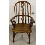 An antique spindle backed yew wood Windsor chair with curved stretcher and turned supports.