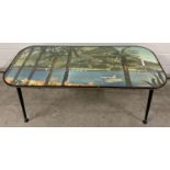 A mid century glass topped coffee table with screw in legs and adjustable feet. Top decorated with a