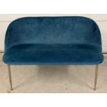 A modern design love seat with tubular brushed steel legs and teal velvet coloured upholstery.