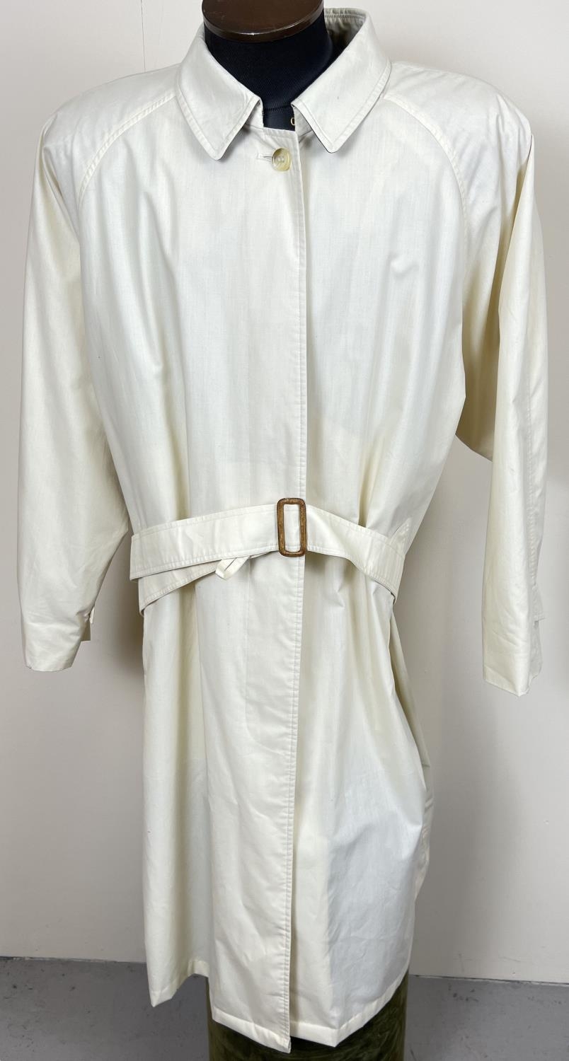 A cream light weight belted trench coat by Burberrys. Front button fastening with 2 front pockets.