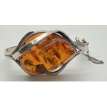 A modern design silver and Baltic amber bangle style bracelet with safety chain. Large central piece