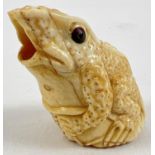 A carved bone? netsuke in the from of a frog sitting on a lily pad, with open mouth. Approx. 5cm