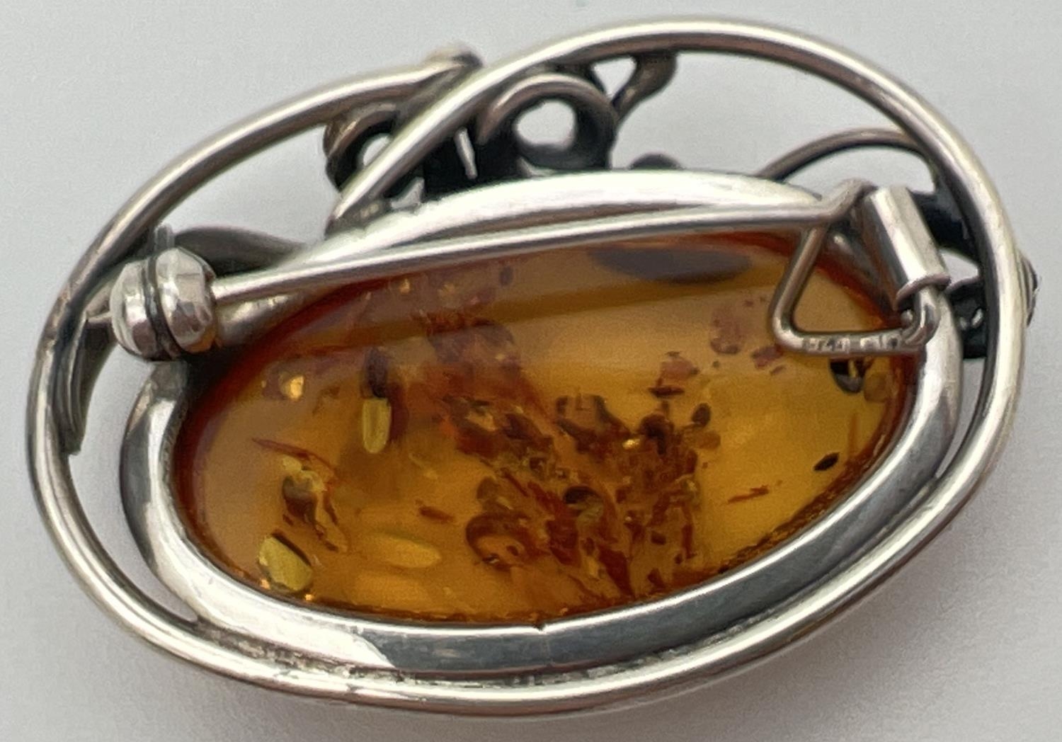 A silver and cognac Baltic amber brooch pendant of Art Nouveau design. With decorative swirl - Image 2 of 2