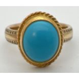 A 9ct gold dress ring set with an oval cabochon of turquoise. Band of ring has studded engraved