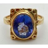 An 18ct yellow gold and tanzanite ring with a decorative square shaped mount. Large oval cut