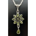 A silver and peridot flower design pendant on an 18" silver belcher chain. Pendant stamped 925 to
