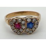 An 18ct gold, ruby, sapphire and diamond ring in a double heart shaped setting. Central round cut