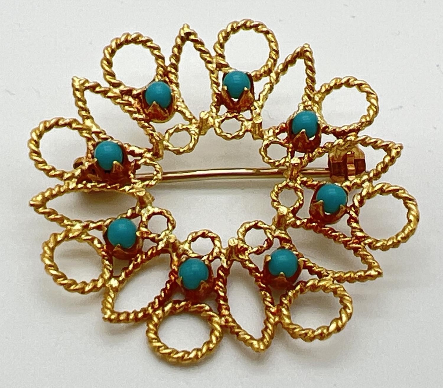 A 18ct gold open work circular brooch set with 8 small round turquoise cabochons. Secure pin to