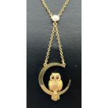 A 9ct gold fixed pendant necklace featuring an owl sitting in a crescent moon. 16" chain necklace