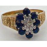 A vintage 9ct gold, sapphire and diamond ring with textured shoulders with floral design. Central