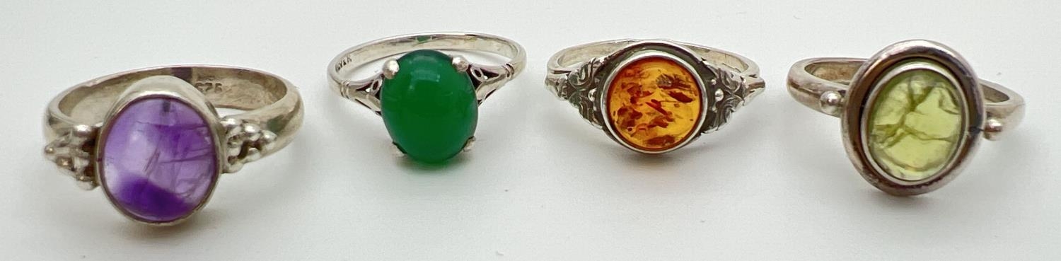 4 silver and natural single stone set dress rings, to include amber, peridot and amethyst. All