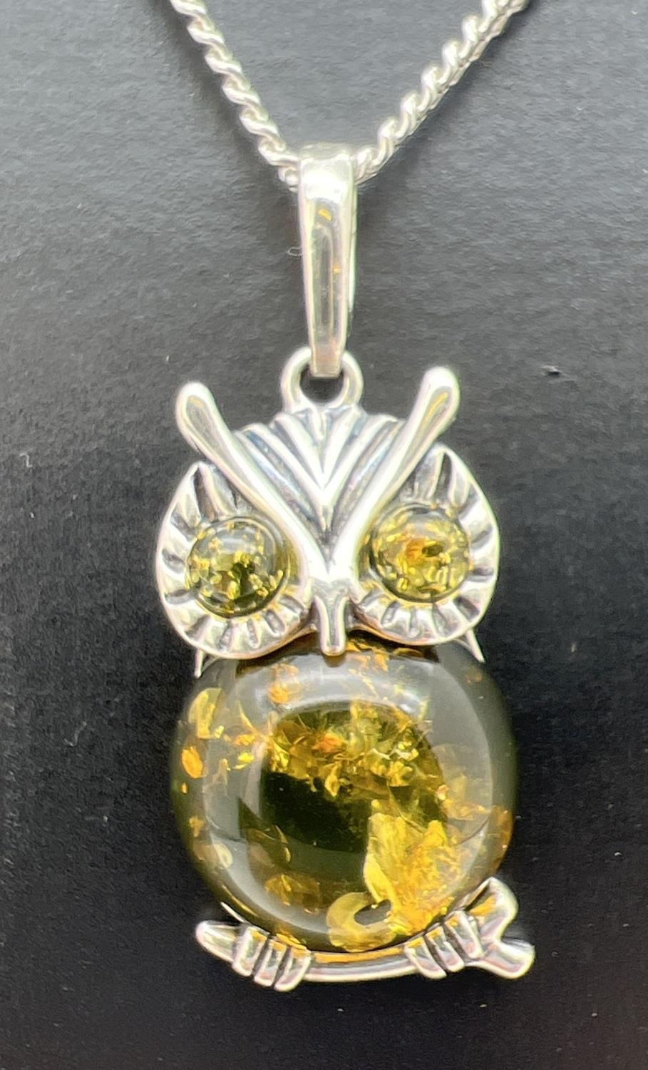 A silver and green amber pendant in the form of an owl, on an 18" silver curb chain. Back of