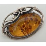 A silver and cognac Baltic amber brooch pendant of Art Nouveau design. With decorative swirl