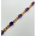 A 9ct yellow gold and amethyst love and kisses style 13 link bracelet of alternating oval cut