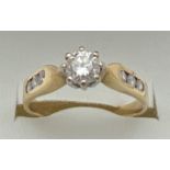 An 18ct gold .33ct diamond solitaire ring with diamond channel set shoulders. Fully hallmarked