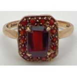A 9ct gold and garnet dress ring with central emerald cut stone in a basket style setting.