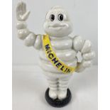 A painted cast iron money bank of a waving Michelin man stood on a tyre. Approx. 22cm tall.