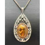 A modern design teardrop shaped amber set pendant with pierced design mount. On a 16 inch curb chain