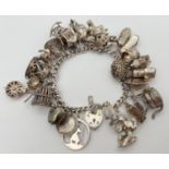 A vintage silver charm bracelet with padlock, safety chain and 27 silver and white metal charms.