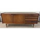 A mid century Afrormosia wood triple sideboard by Richard Hornby for Heals. Raised on tapered