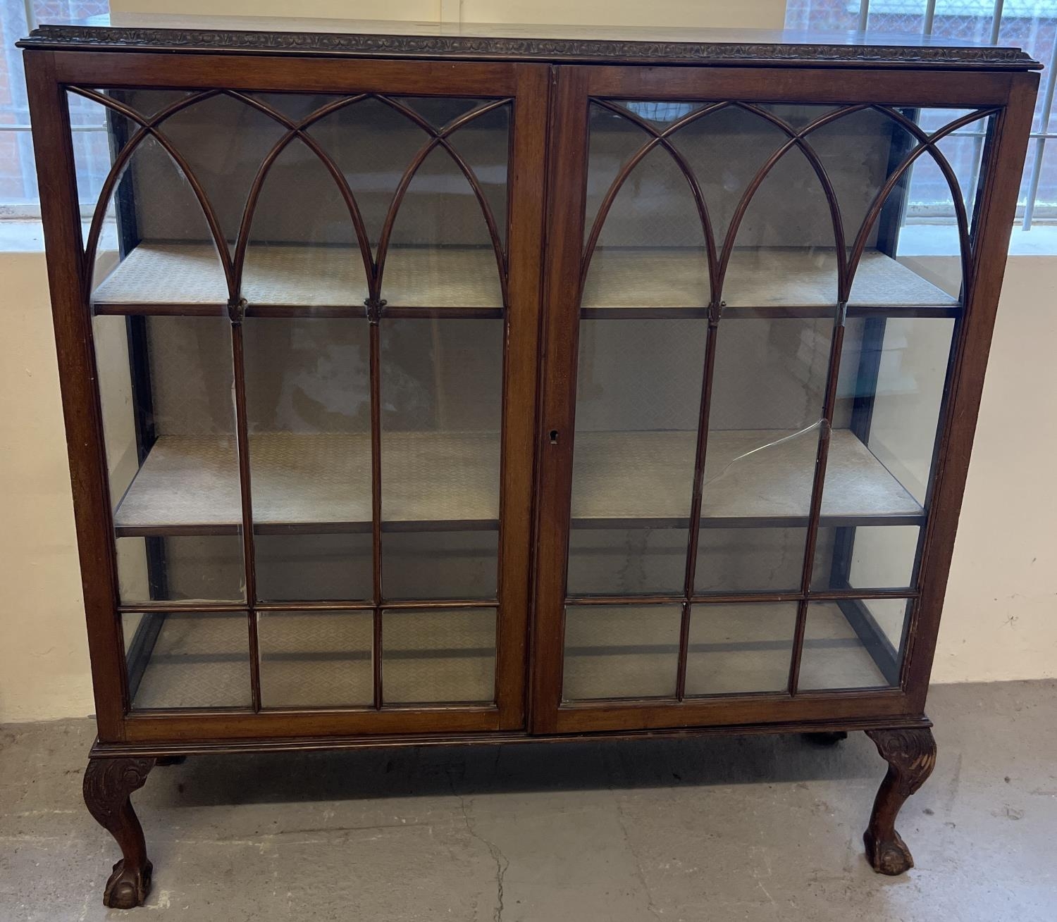 A vintage dark wood 2 door glass display cabinet raised on 4 ball & claw footed legs. Fabric lined