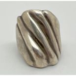 A contemporary design large silver dress ring. Rough grooved detail to top of ring. Worn 925 mark to