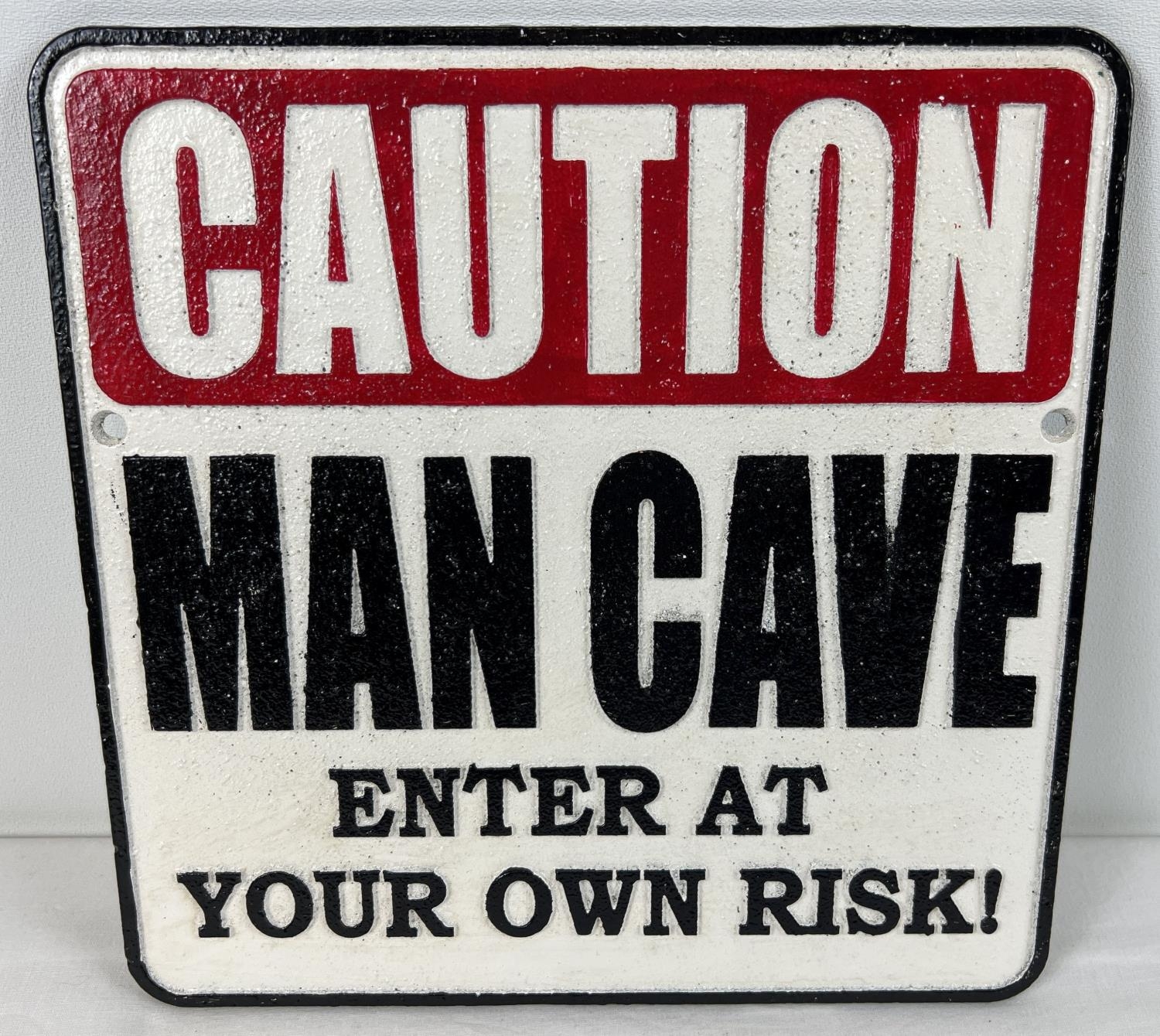 A painted cast iron Man Cave wall plaque, with fixing holes. In red, black and white. Approx. 24.