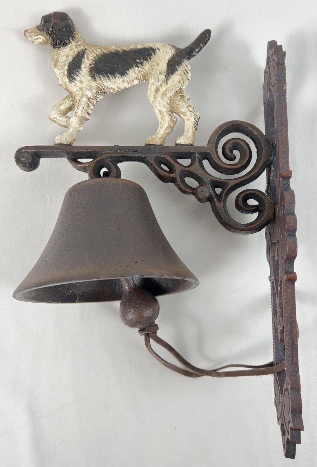 A cast iron wall mountable garden bell with painted dog detail. Approx. 35cm tall.