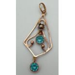 An Art Nouveau 9ct rose gold floral detail drop pendant set with 2 round cut bezel set blue topaz