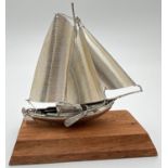A vintage silver model of a sailing boat mounted on a wooden plinth. Very well detailed with matte