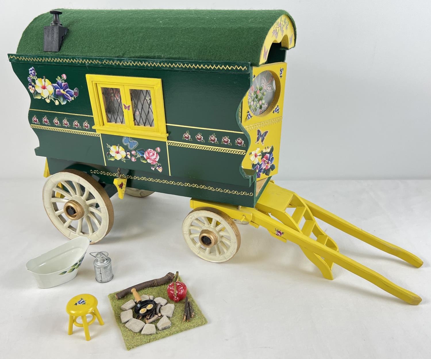 A painted wooden model of a Gypsy caravan with hand painted and sticker detail and green felt