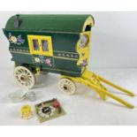 A painted wooden model of a Gypsy caravan with hand painted and sticker detail and green felt
