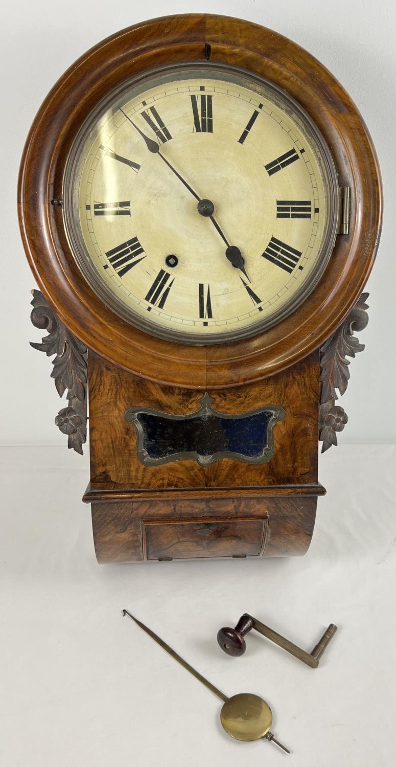 A walnut veneer wooden cased antique wall handing clock with striking bell to top. Carved floral