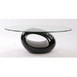 20th Century glass coffee table. the oval glass top above the black oval shaped base, 110cm long,