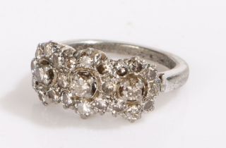 Indian white metal and diamond set ring, with twenty-five diamonds forming three flower heads, 3.9