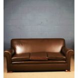 Brown leather upholstered three seater settee, with scrolled arms and wooden block feet, 187cm long