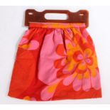 1960's plastic and fabric bag, the orange plastic handles above the bright red, orange and pink bag,