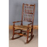Oak spindle back and rush seated rocking chair, 98cm tall