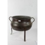 Arts and Crafts style copper cauldron, with carrying handle either side, raised on three legs,