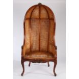 A Louis XV style double Bergere canopy hall or porters chair, with exposed carved show wood frame,