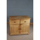 Pine cupboard, with two frieze drawers above two arched panelled cupboard doors, raised on bun feet,