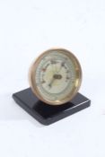 Edwardian brass cased desk barometer, with silvered dial, raised on a black plinth base, 7.5cm wide,