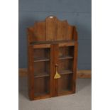 Pine display cabinet, the shaped frieze above two glazed doors opening to reveal two interior