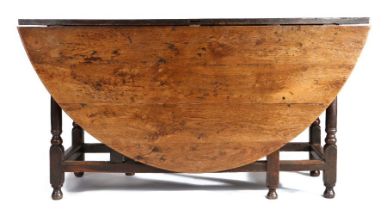 A large 18th Century oak gateleg table, the oval drop leaf table above a shallow frieze, one end