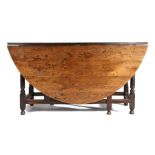 A large 18th Century oak gateleg table, the oval drop leaf table above a shallow frieze, one end