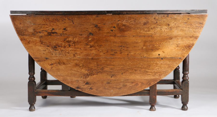 A large 18th Century oak gateleg table, the oval drop leaf table above a shallow frieze, one end - Image 2 of 5