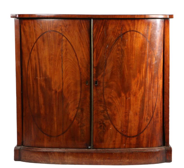 Regency mahogany bowfronted cabinet, the top above a pair of doors with oval stringing enclosing
