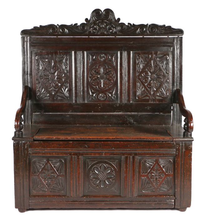 17th Century style oak bench, the carved and arched pediment above three carved panels, and a hinged