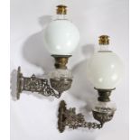 Near pair of wall mounted oil lamps, the pierced scroll decorated cast iron brackets housing the