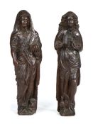 Two 17th Century carved oak standing figures, the first clutching a book in one hand, the other hand